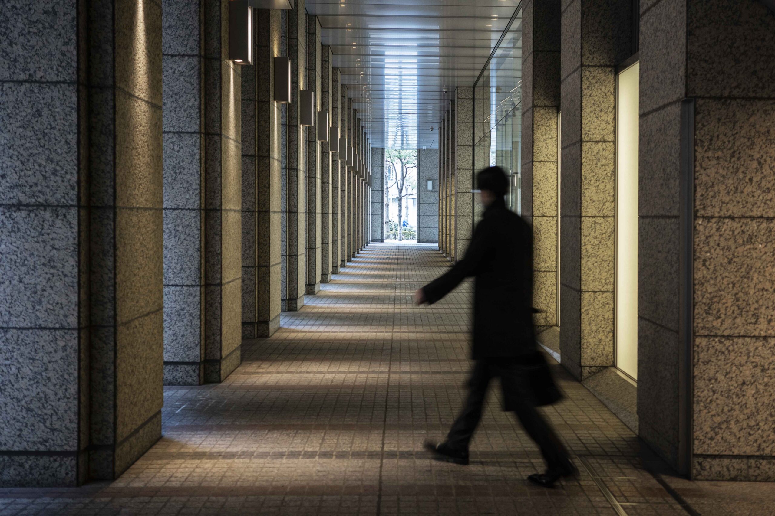 Professional walking through a corporate building colonnade at dusk